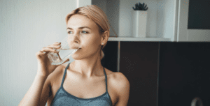Young fitness lady drinking water after yoga exercises wearing sportswear at home dry mouth general dentistry dentist in Columbia South Carolina